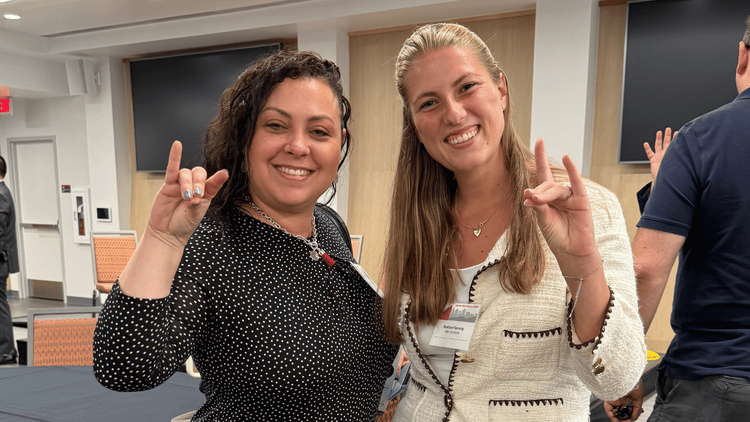 Two Jenkins MBA alumni flash the wolf sign with their hands.