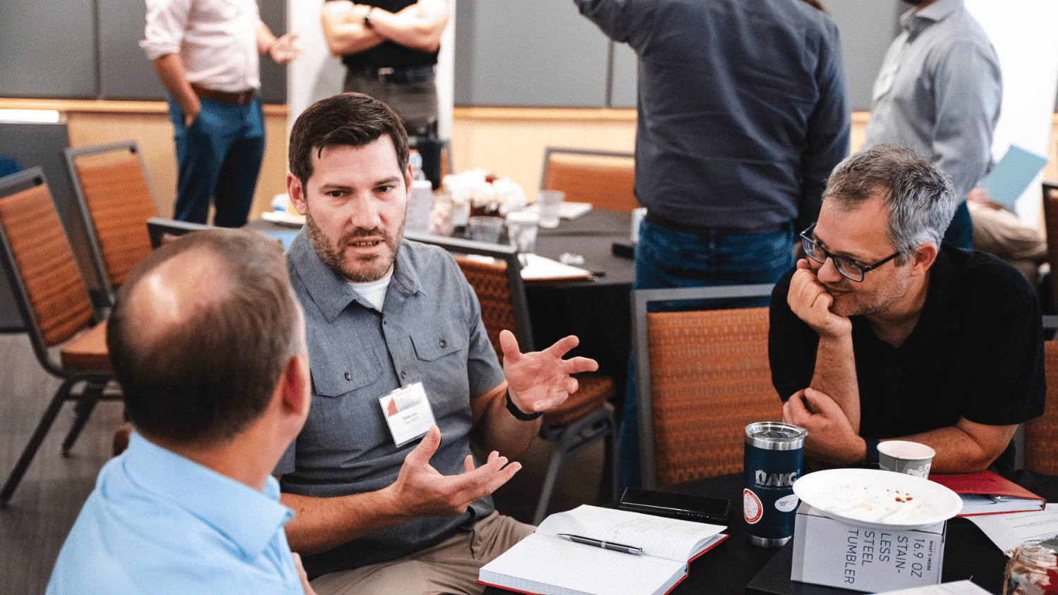 Three Jenkins MBA alumni talk while seated around a table.