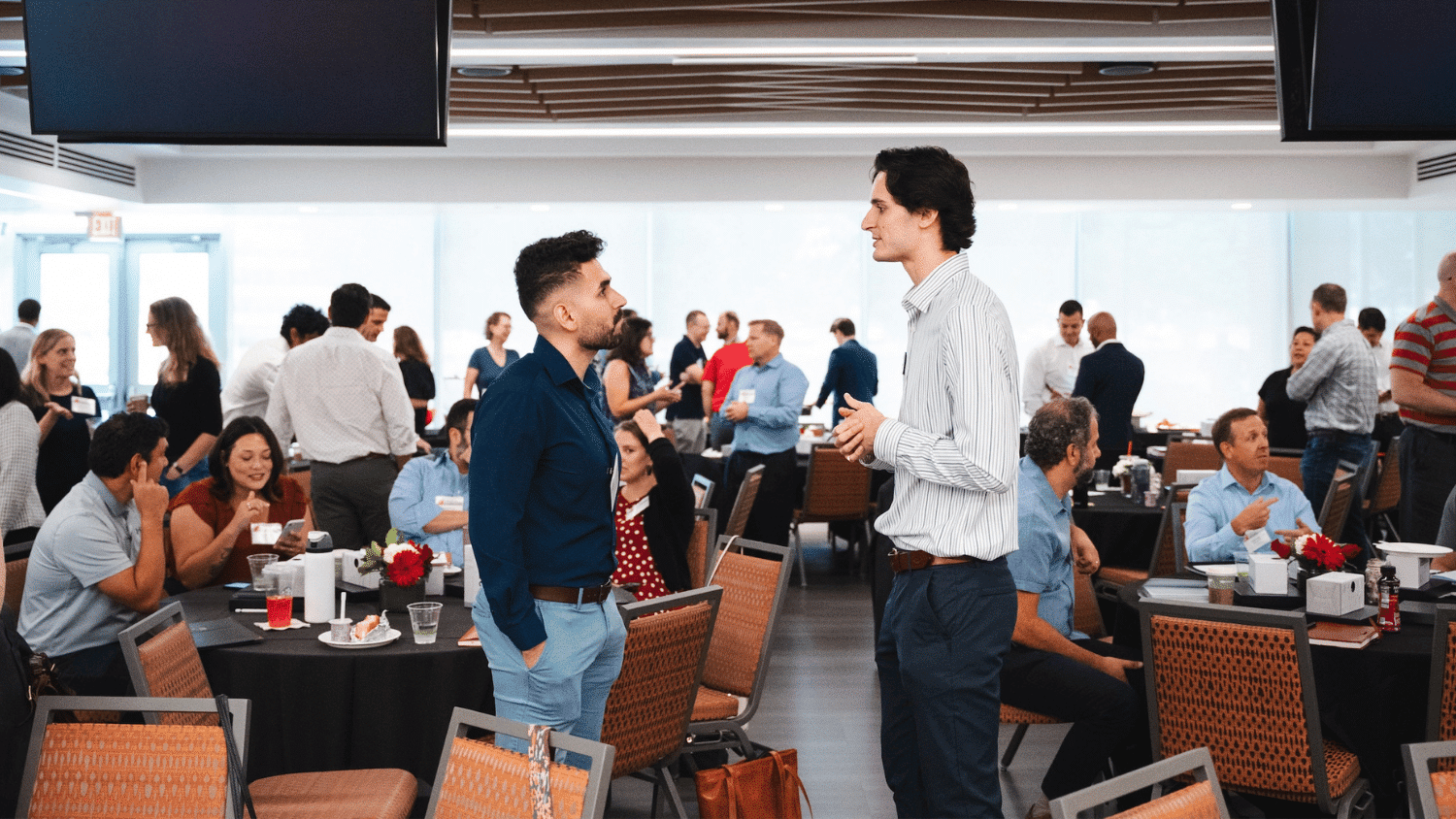 Two Jenkins MBA alumni males talk in a group of people.